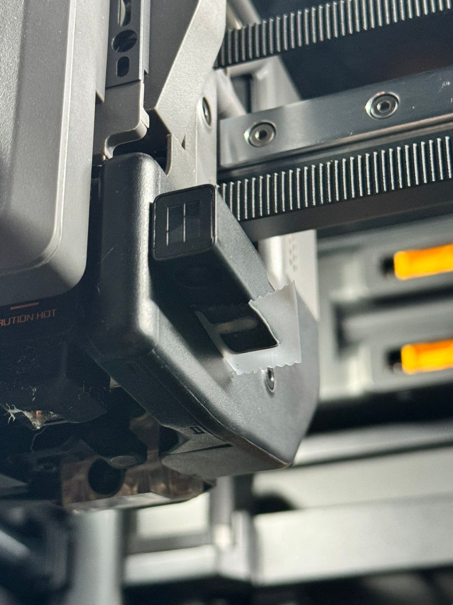 A close-up view of a Bambu Lab H2D tool head with a small piece of tape covering the lighting module.