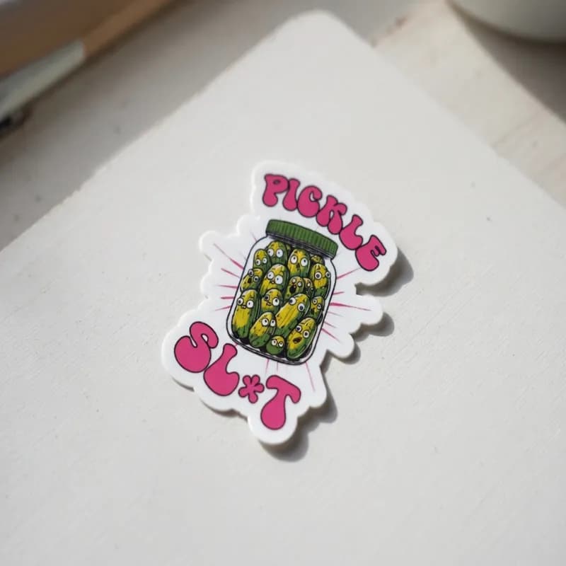 A colorful sticker featuring a jar filled with cartoon pickles and the text "PICKLE SL*T" in bold pink letters.